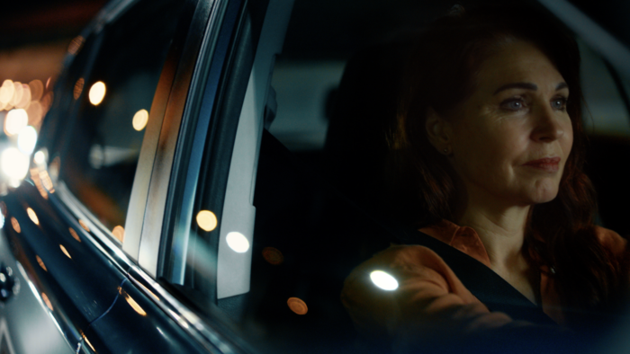 Peachy Keen Colourist Angela Cerasi colour graded this shot from the outside of a car at night, looking at a woman with an orange shirt driving, a tentative smile on her face, for the "Celebrating Mothers" TVC campaign for Mater Mothers Hospital