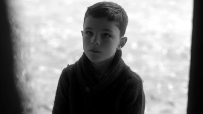 Image of a black and white shot of a young boy staring up at something offscreen, from the colour grade of the documentary "The Jewish Nazi"