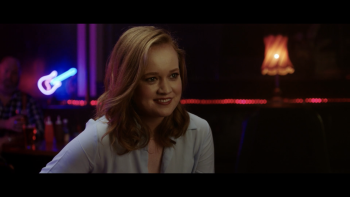 Angela Cerasi's colour grade of the main character Jade sitting at a bar and smiling, for the short film "The Hitchhiker"